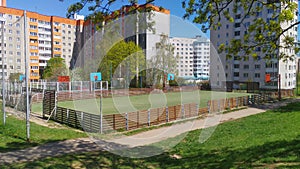 In the city quarter, among residential buildings, next to grass lawns and trees, there are sports grounds for basketball and footb