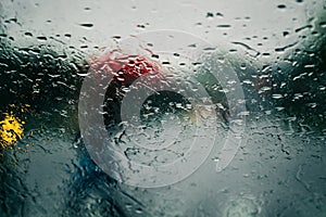 City road seen through rain drops on the car windshield