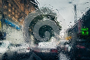 City road seen through rain drops on the car windshield