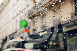 City road seen through rain drops on the car windshield