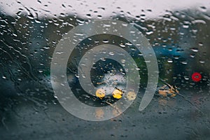 City road seen through rain drops on the car windshield