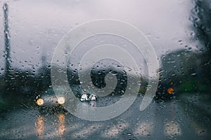 City road seen through rain drops on the car windshield