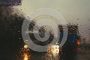 City road seen through rain drops on the car windshield