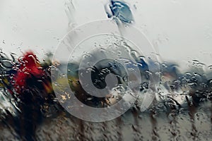 City road seen through rain drops on the car windshield