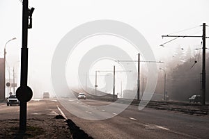 City road or street with car traffic in morning spring fog or haze, atmospheric urban photo