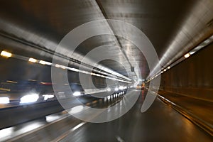 Road traffic in rainy night tunnel with cars and lights blur effect