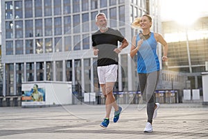 City running middle aged couple jogging together in the morning while training outdoors