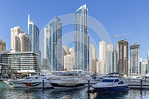 City scape with modern high-rise buildings, man made river with yachts and blue sky in background at Dubai