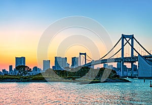 City skyline and Rainbow bridge across Tokyo Bay in sunset. Odaiba, Tokyo, Japan