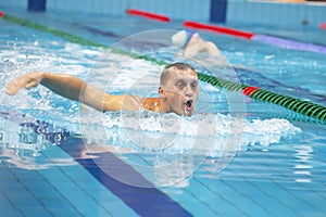 City sports pool. Male swimmer swims in the pool