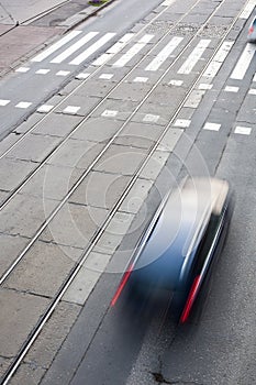 City street with a crossing, rail, motion blurred traffic