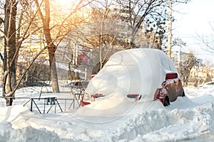 City street driveway parking lot spot with small car covered snow stuck trapped after heavy blizzard snowfall winter day