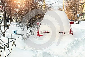 City street driveway parking lot spot with small car covered snow stuck trapped after heavy blizzard snowfall winter day