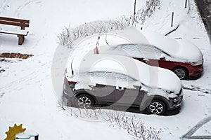 City street driveway parking lot spot with small car covered snow stuck trapped after heavy blizzard snowfall winter day
