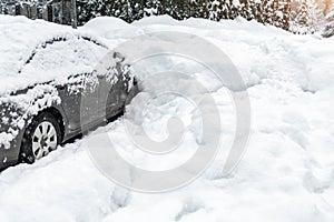 City street driveway parking lot spot with small car covered snow stuck trapped after heavy blizzard snowfall winter day