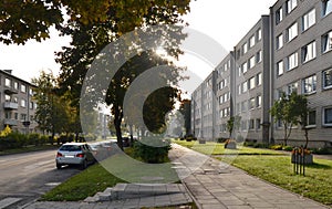 City street with empty road and morning light - cars, houses, sidewalk, lawn and vegetation