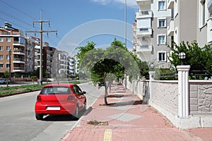 City street with parked red car in the sunny summer day