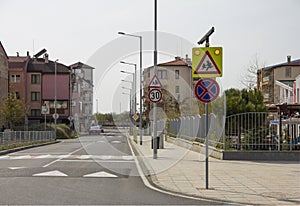 City street with a pedestrian crossing, a speed bump and a caution sign `children` near a beautiful kindergarten.