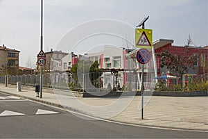 City street with a pedestrian crossing, a speed bump and a caution sign `children` near a beautiful kindergarten.