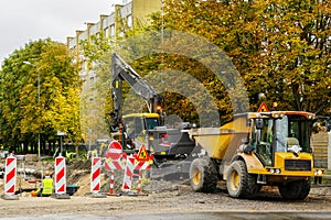 City street rebuilding view, hydraulic excavator, yellow dump truck, warning signs