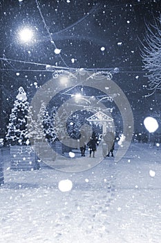 City street snowfall at winter night. New Year Christmas holidays celebration.
