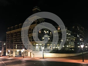 The city streets of scheveningen by night with a big apartments building complex and lots of lampposts