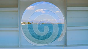 City summer landscape view of Greece seen from inside a ship cabin with round peep-hole window. Round window in a shabby