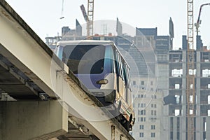 City train car on high railroad over street traffic between skyscraper buildings in modern American megapolis. Urban