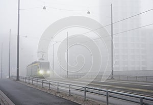 a city tram travels through the city in heavy fog