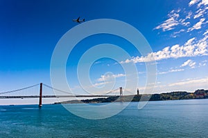 Cityscape with 25 April Bridge over the Tagus river and airplane in Lisbon