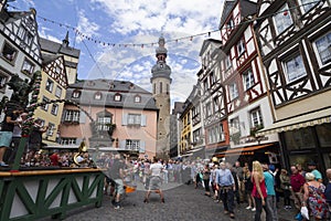 Cityscape of Cochem with its typical half-timbered houses and restaurants. Market square with town hall in background, people cele