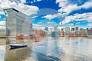 Cityscape of downtown Oslo with modern architecture, boat with a group of people and the blue sky with clouds, Norway