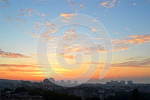 Cityscape in the early morning: pink and orange clouds on a blue sky at dawn just before sunrise over the sleeping city