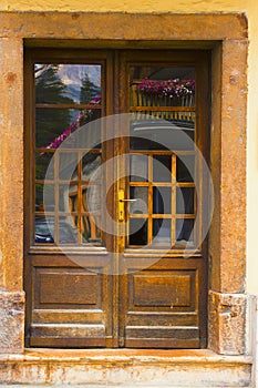 Cityscape of FaÃ§ade and door with reflection of flowers on balconies, in Cortina dAmpezzo, Province of Belluno, Italy photo