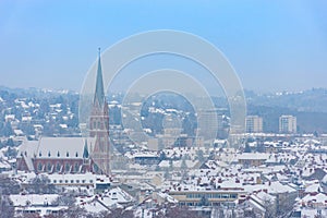 Cityscape of Graz with Church of the Sacred Heart of Jesus and historic buildings rooftops with snow, in Graz, Styria region,