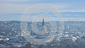 Cityscape of Graz with Church of the Sacred Heart of Jesus and historic buildings rooftops with snow, in Graz, Styria region,