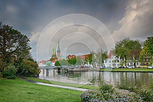 Cityscape of the historic old town of Luebeck, Germany at the river Trave, dramatic sky with clouds, copy space