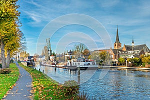 Cityscape of Koudekerk aan den Rijn with sailing sand loaded ship on the Oude Rijn river