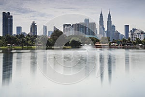 Cityscape of Kuala Lumpur at noon with Petronas Towers reflected on the Titiwangsa Lake