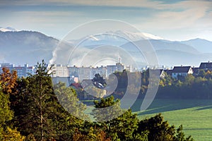 Panoráma města se svěžími stromy uprostřed hornatého terénu v pozadí. Banská Bystrica, Slovensko.