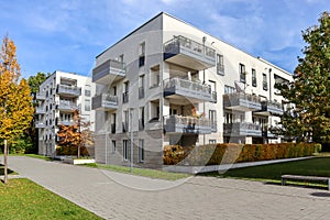 Cityscape with modern residential area, new apartment buildings and green courtyard with pedestrian walkway and trees in autumn