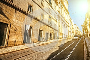 Cityscape of the old city in Lisbon with a steeply rising street with tram tracks and facades of old houses. Perspective view of