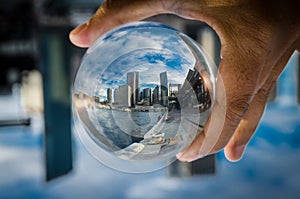 Cityscape photography in a clear glass crystal ball with dramatic clouds sky.