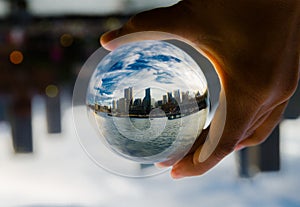 Cityscape photography in a clear glass crystal ball with dramatic clouds sky.