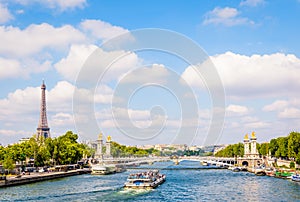 Cityscape of the river Seine in Paris, France, with a bateau-mouche, the pont Alexandre III and the Eiffel tower by a sunny day