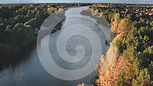 Cityscape at river shore aerial. Autumn nobody nature landscape. Colorful leafy trees forest sun day