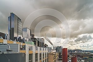 Cityscape of Seattle with dark clouds and dark vapor rising from smoke stack