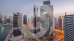 Cityscape of skyscrapers in Dubai Business Bay with water canal aerial night to day timelapse