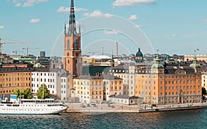 Cityscape with towers of Stockholm, water around and touristic boat on cruise through the islands.