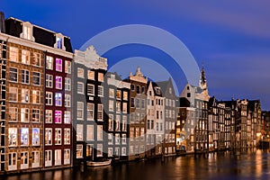 Cityscape of traditional Dutch houses during blue hour at the Damrak canal in Amsterdam